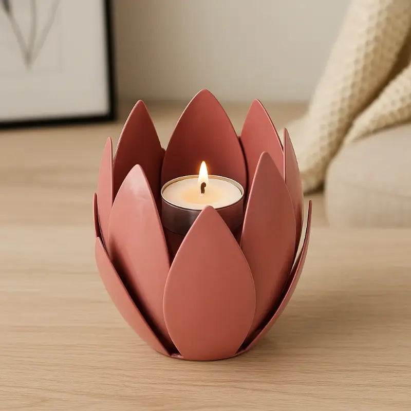 Pink lotus-shaped candle holder with a lit candle on a wooden surface.