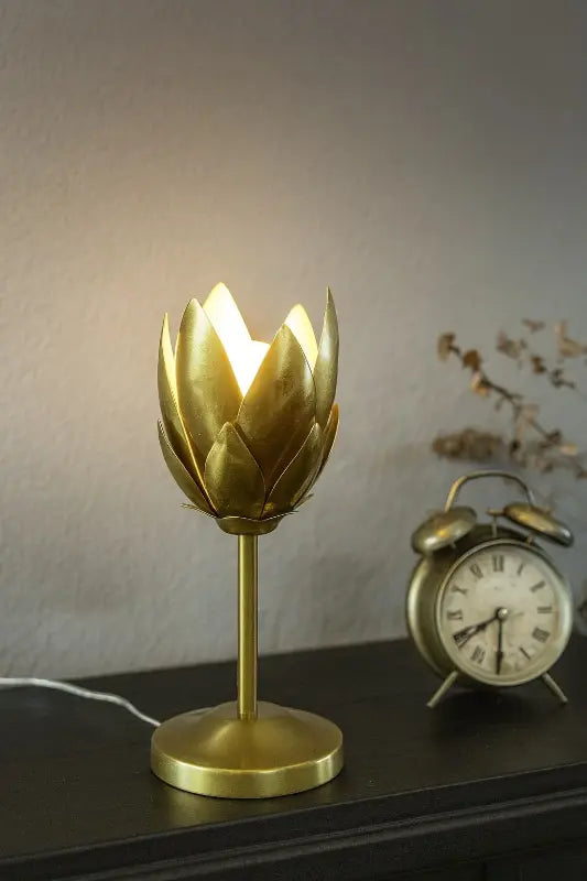 Gold artichoke-shaped lamp on a table next to a vintage-style alarm clock.