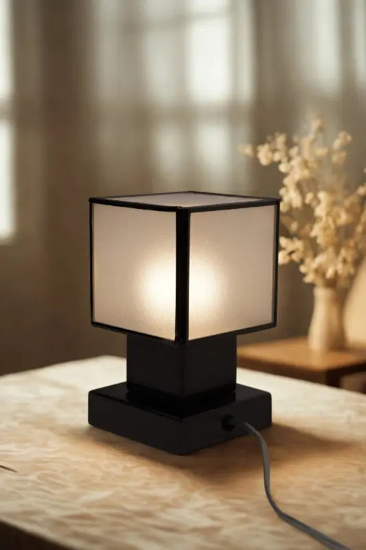 Table lamp with a white shade and black base on a wooden surface.