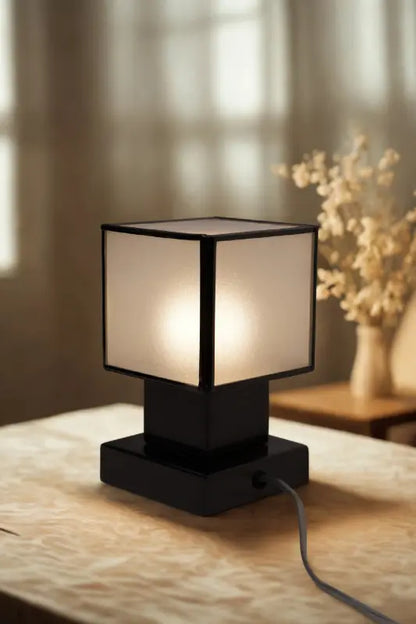Table lamp with a white shade and black base on a wooden surface.