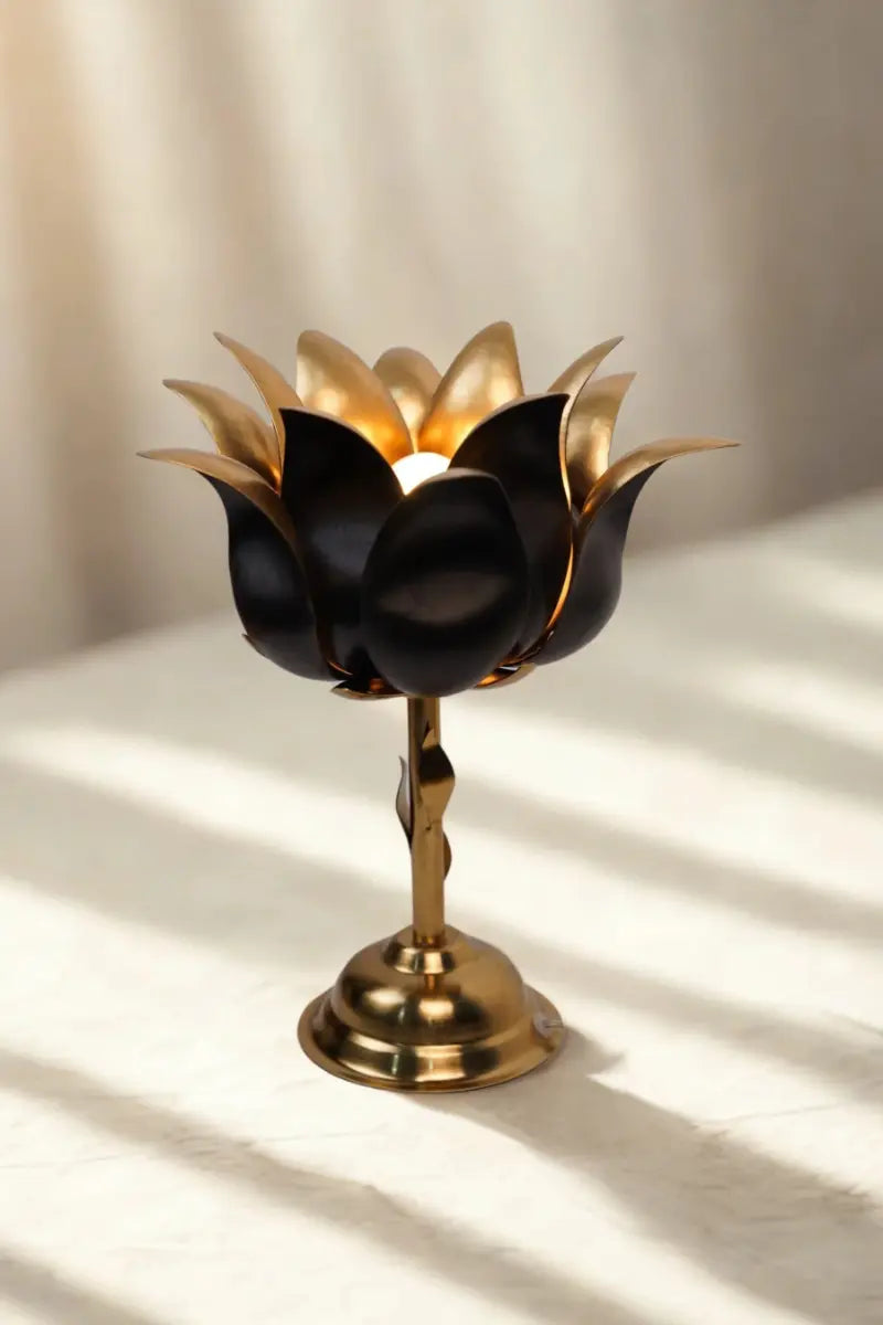 Decorative black and gold lotus lamp on a white surface with soft shadows