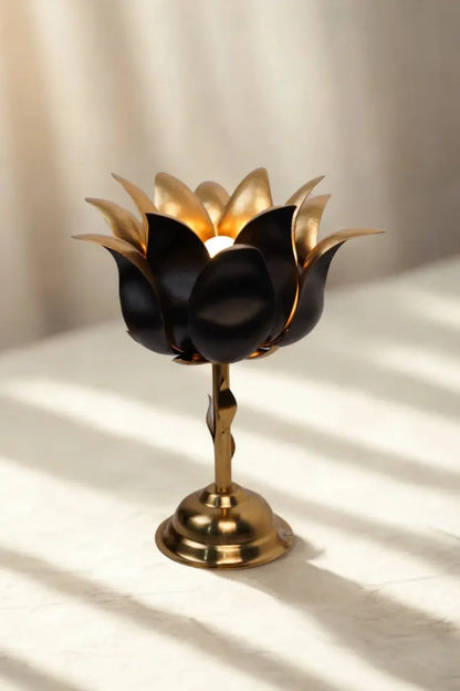 Decorative black and gold lotus lamp on a white surface with soft shadows