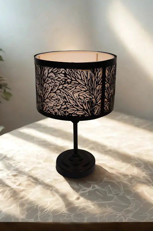 Black table lamp with decorative shade on a light surface