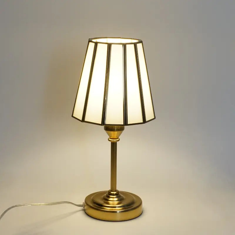 Table lamp with a white shade and gold base on a neutral background