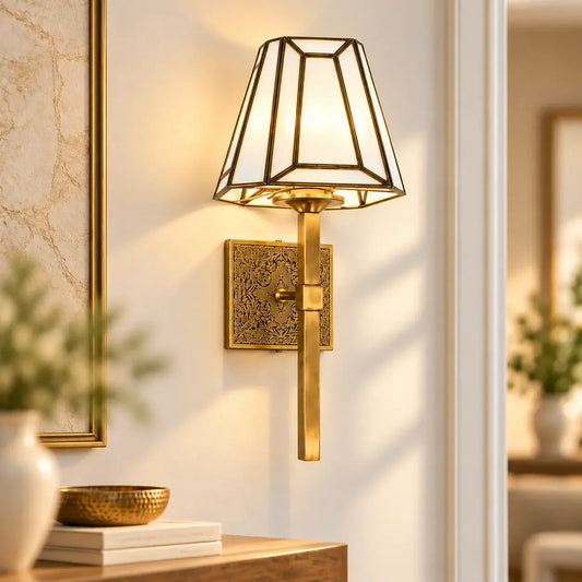 Antique Brass Geometric Wall Sconce by ILLUMEA with a decorative engraved backplate, long vertical arm, and contemporary faceted glass shade